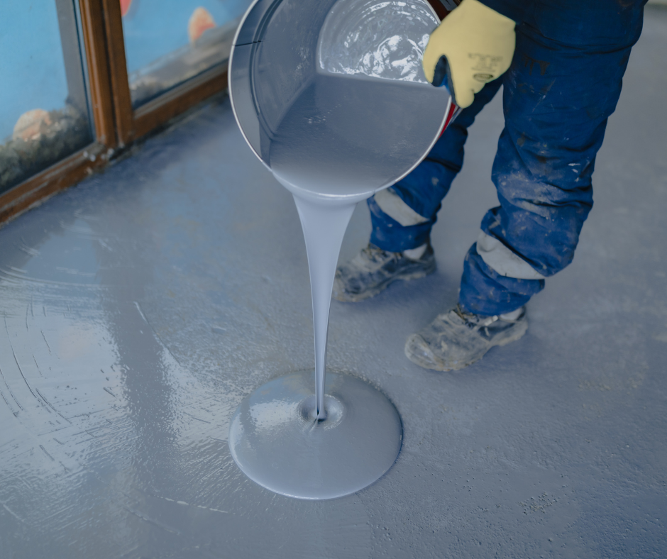 Industrial floor being coated with grey epoxy resin during initial pour