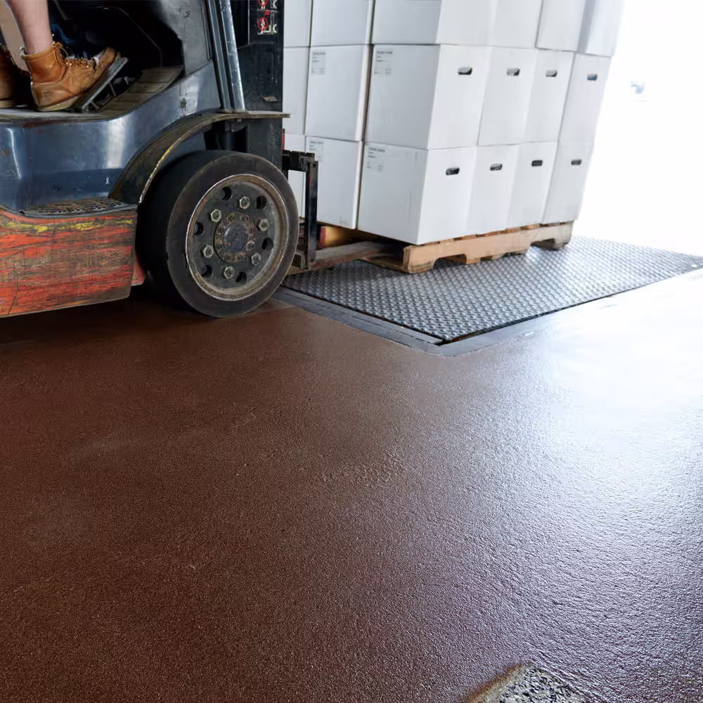 Forklift driving over a quartz concrete floor coating in a commercial facility.